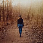 Frau im Blazer und Jeans spaziert im Herbstpark