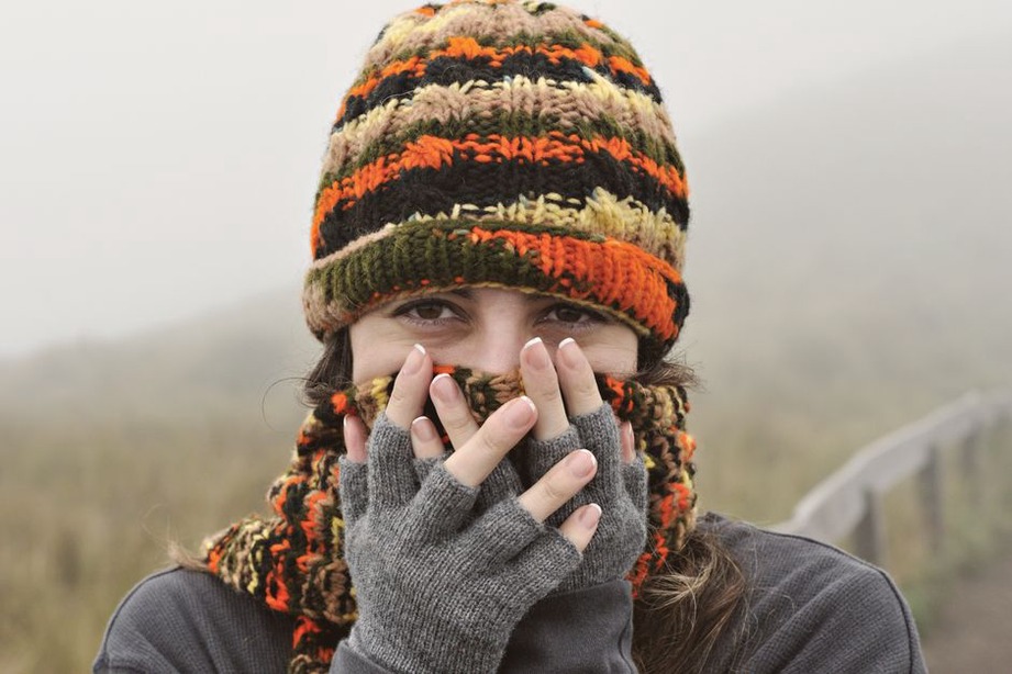 Frau mit gestricktem Schal und Handschuhen an einem kühlen Tag