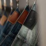 dunkelblaue Skinny-Jeans auf Holzbügel vor neutralem Hintergrund