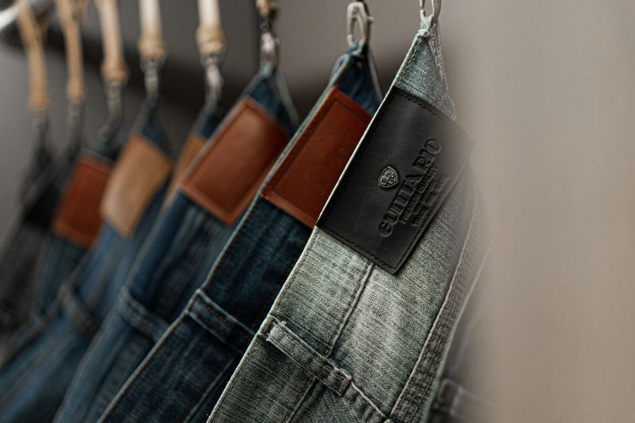dunkelblaue Skinny-Jeans auf Holzbügel vor neutralem Hintergrund