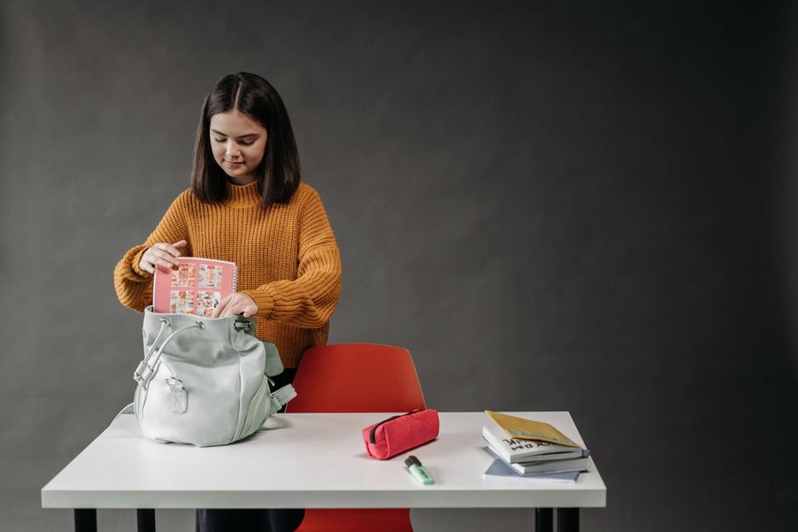 Rucksack mit Unterlagen neben einem grauen Cardigan