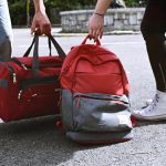 Jeans und Cardigan liegen griffbereit neben der Reisetasche