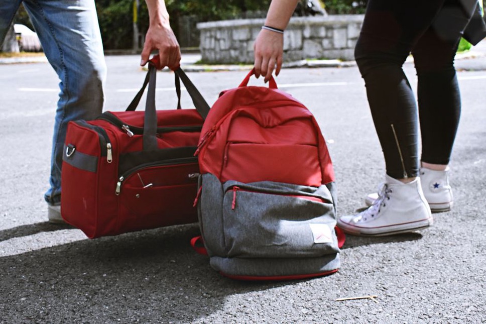 Jeans und Cardigan liegen griffbereit neben der Reisetasche